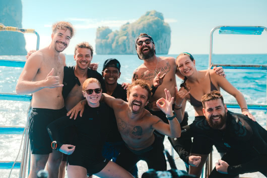 Group of happy divers posing on a boat after a dive near limestone islands in Phi Phi, Thailand
