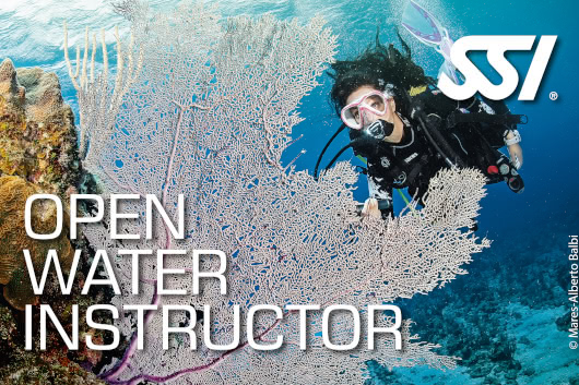 Scuba instructor demonstrating a breathing technique and hand signal during a classroom session