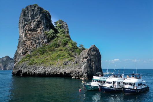 Island Divers dive boats moored near the Koh Bida islands, featuring dramatic limestone cliffs in Phi Phi, Thailand