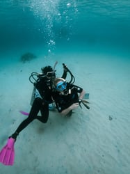 Scuba instructor guiding a student through a breathing exercise on the sandy sea floor